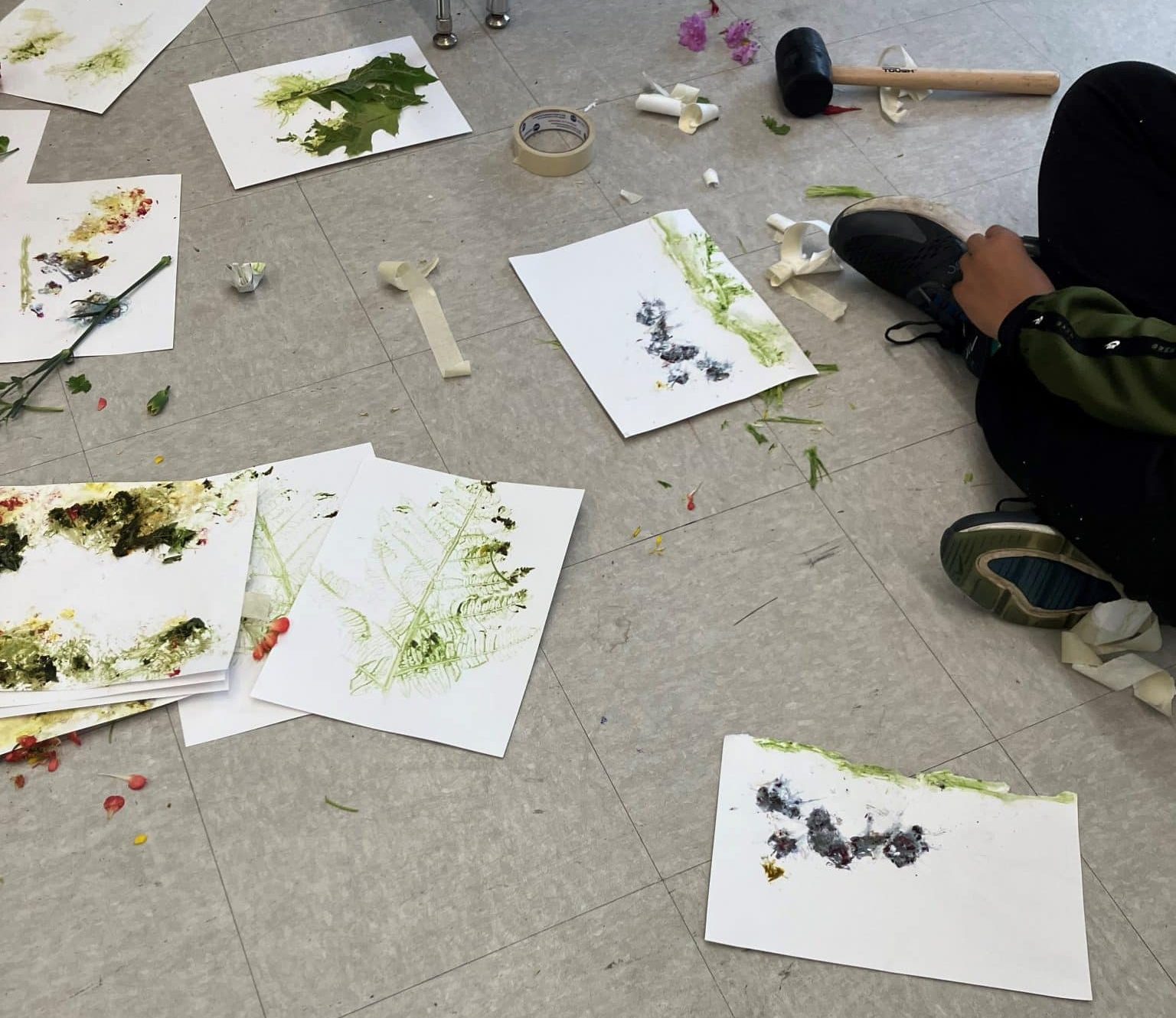 Unidentified student creating plant pounding art surrounded by previous pieces.