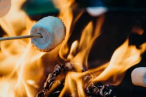 Marshmallow roasting on a stick over a blazing campfire.